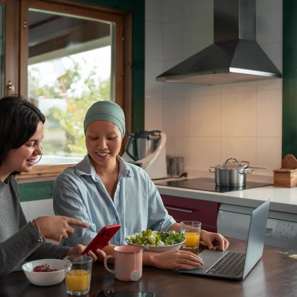 portrait-woman-with-cancer-using-laptop-with-friend-home